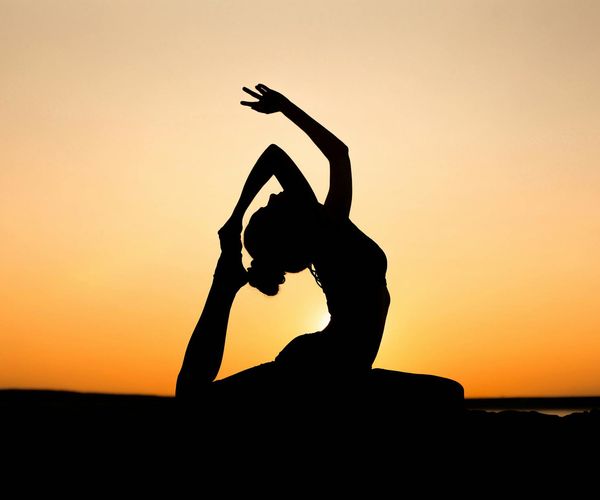 Silhouette of a person in a yoga pose against a beautiful sunset.